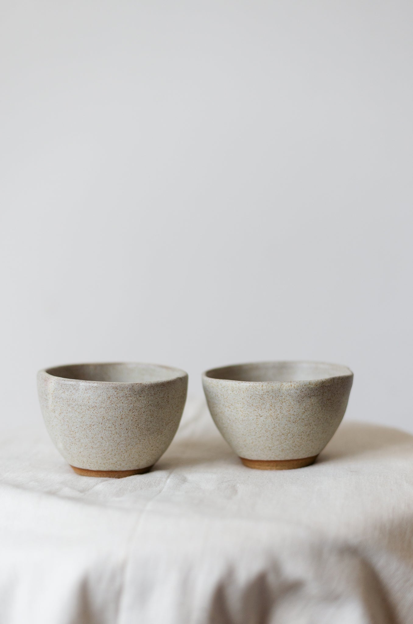 Minimalistisk håndlaget dessertskål i hvitt stentøy med en glatt, matt glasur.