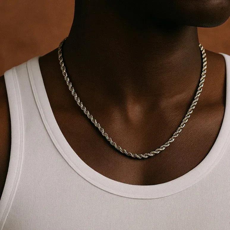 Person wearing a silver chain necklace with a white tank top