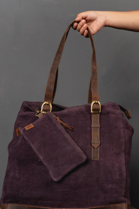 Purple bag with a matching pouch held by a hand against a gray background