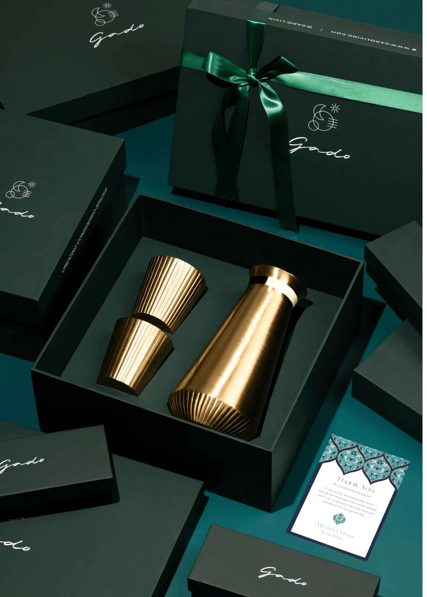 Gold drinkware set in a black box with 'Gado' branding on a teal background