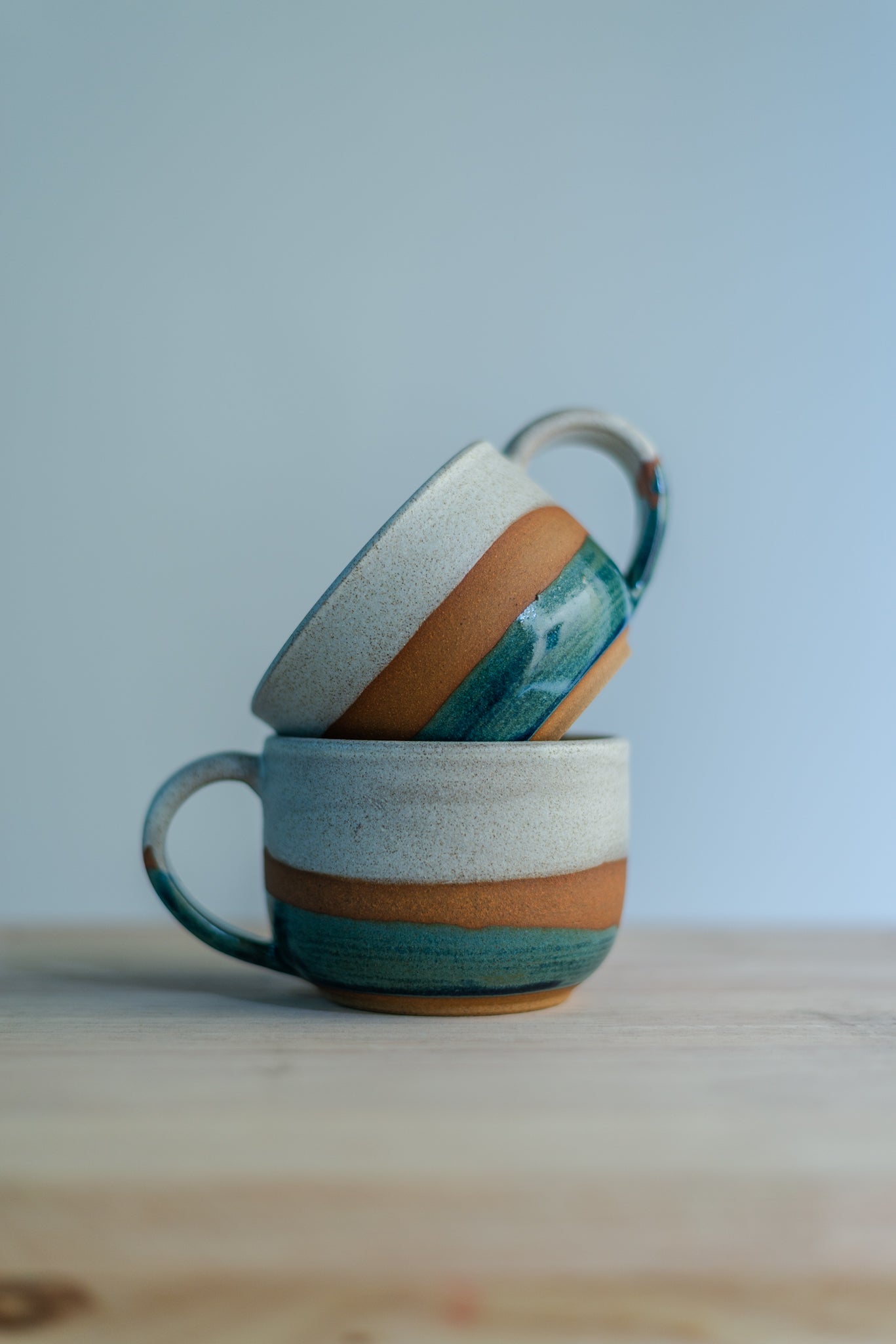 Et rykende varmt håndlaget keramikkrus holdt i to hender, som viser den rå og håndskårne teksturen i leiren.