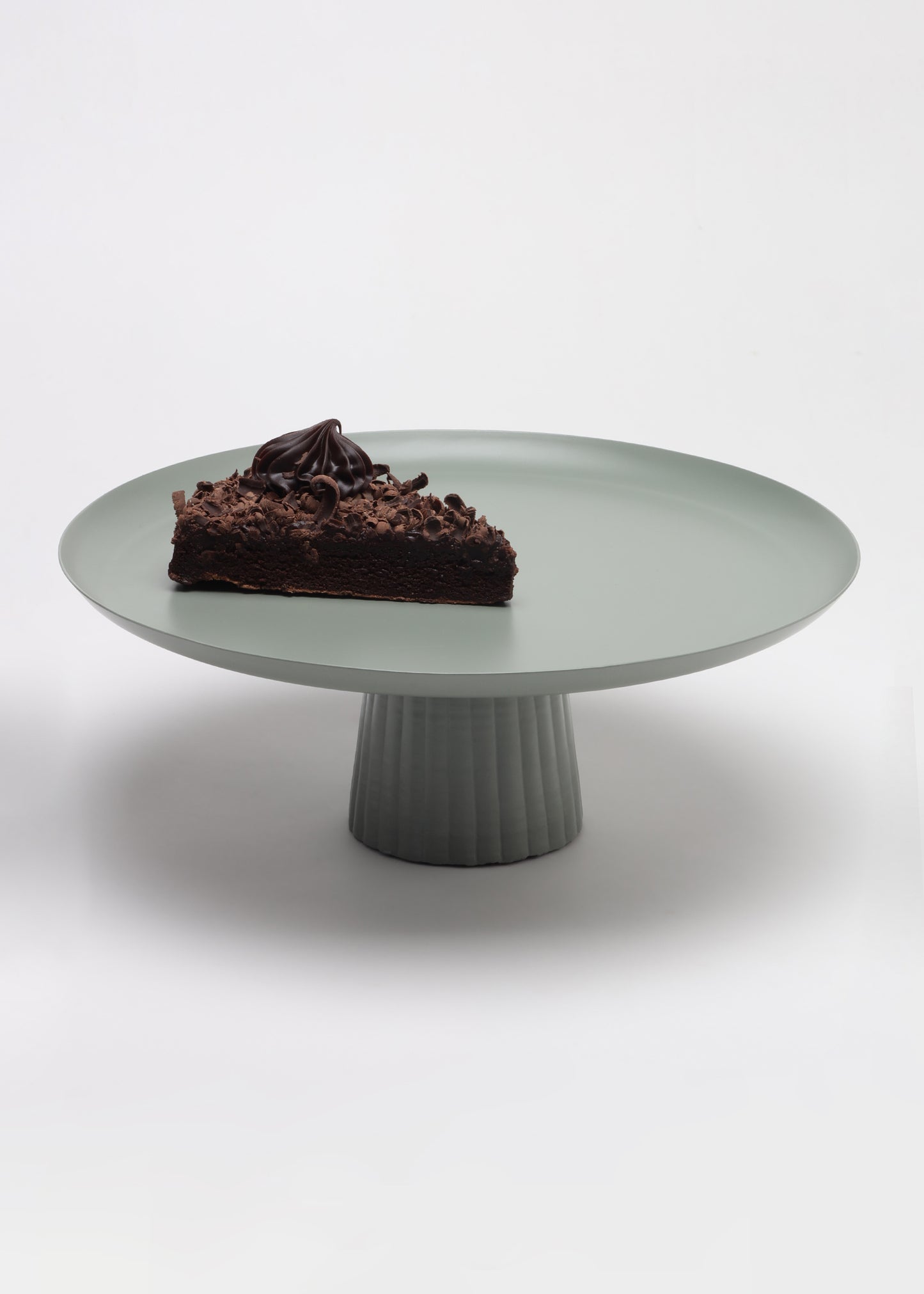 Chocolate cake on a green cake stand against a white background