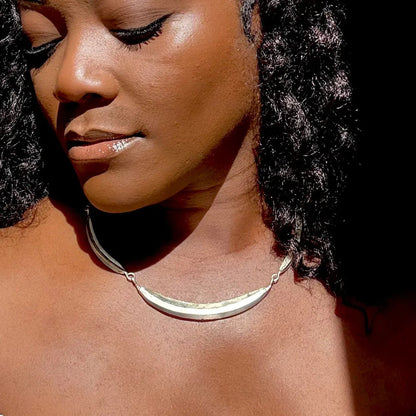 Close-up of a woman wearing a silver necklace with a blurred background