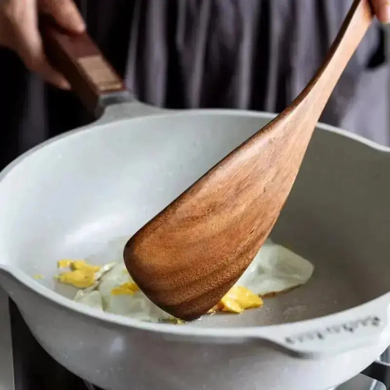 Wooden spatula stirring food in a white pan