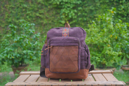 Purple and brown backpack on a wooden table with a green blurred background