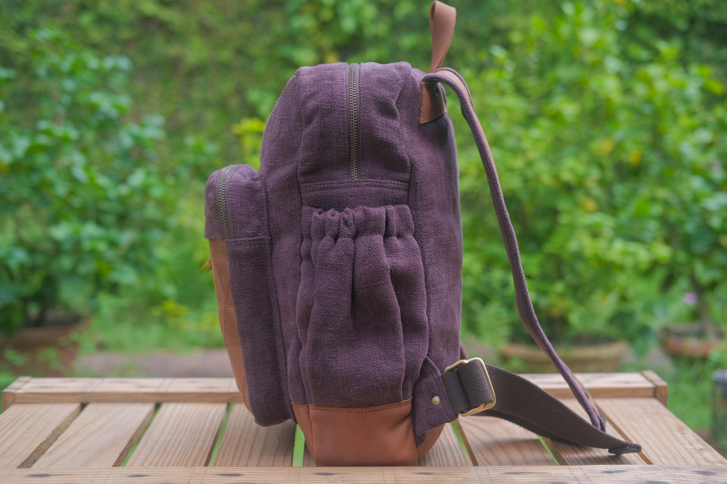 Purple backpack with brown accents on a wooden table outdoors