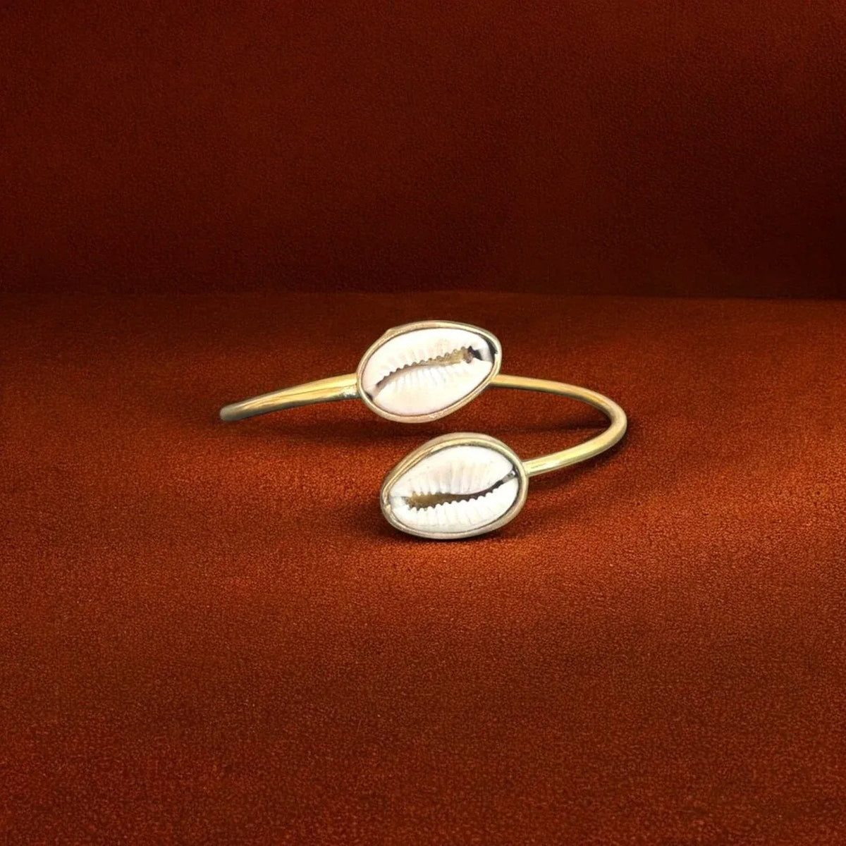 Gold bangles with shell designs on a red background
