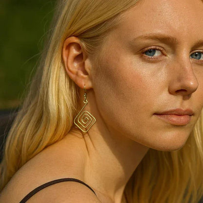 Close-up of a woman wearing gold hoop earrings with a blurred natural background