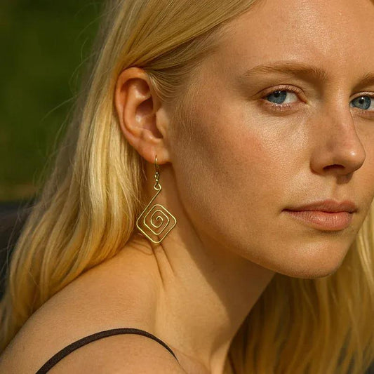 Close-up of a woman wearing gold hoop earrings with a blurred natural background
