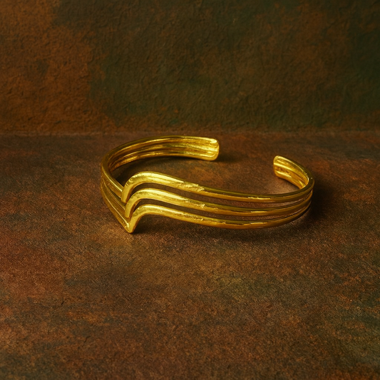 Close-up of the polished brass surface and sculptural movement of the wave-inspired cuff.