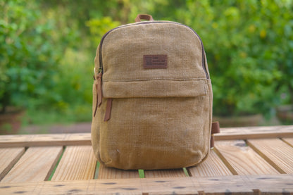 Beige backpack on a wooden table with a blurred green background