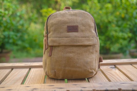 Beige backpack on a wooden table with a blurred green background