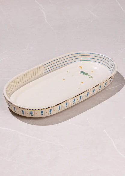 Decorative oval ceramic tray with blue and green patterns on a light gray background