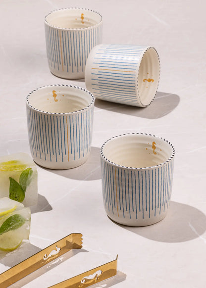 Set of four striped candles on a light surface with a glass of water and lemon slices.