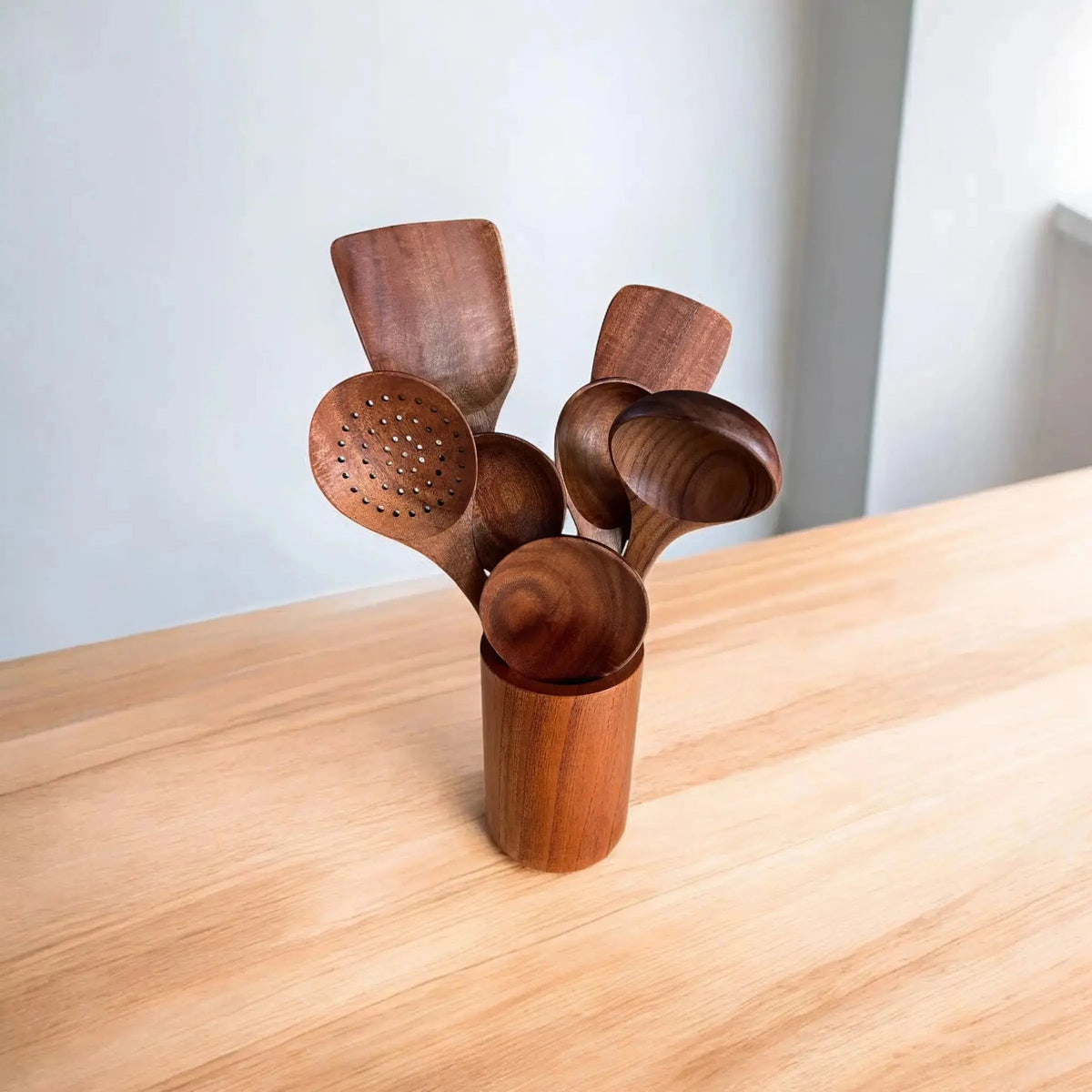 Set of wooden spoons in a holder on a light wood surface