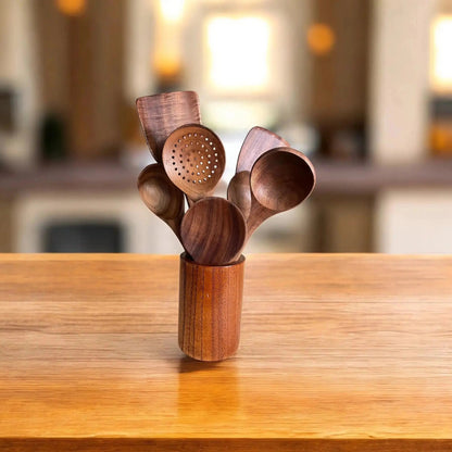 Set of wooden kitchen utensils in a holder on a wooden surface with a blurred background