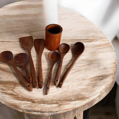 Set of wooden spoons and a small wooden cup on a round wooden table.