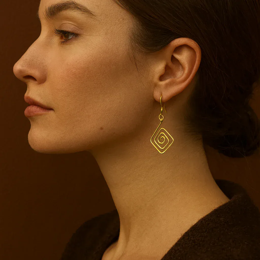 Woman wearing a gold spiral earring against a warm brown background