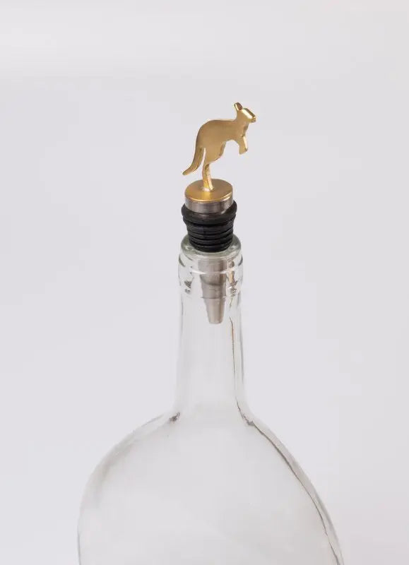 A clear glass bottle with a gold kangaroo-shaped bottle stopper and a black rubber seal, shown against a plain light gray background.