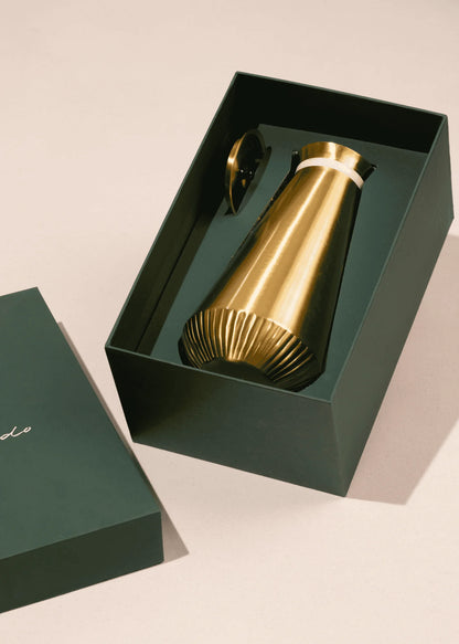 Gold metallic bottle in a green box on a beige background