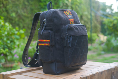 Black backpack with colorful accents on a wooden surface with a blurred green outdoor background