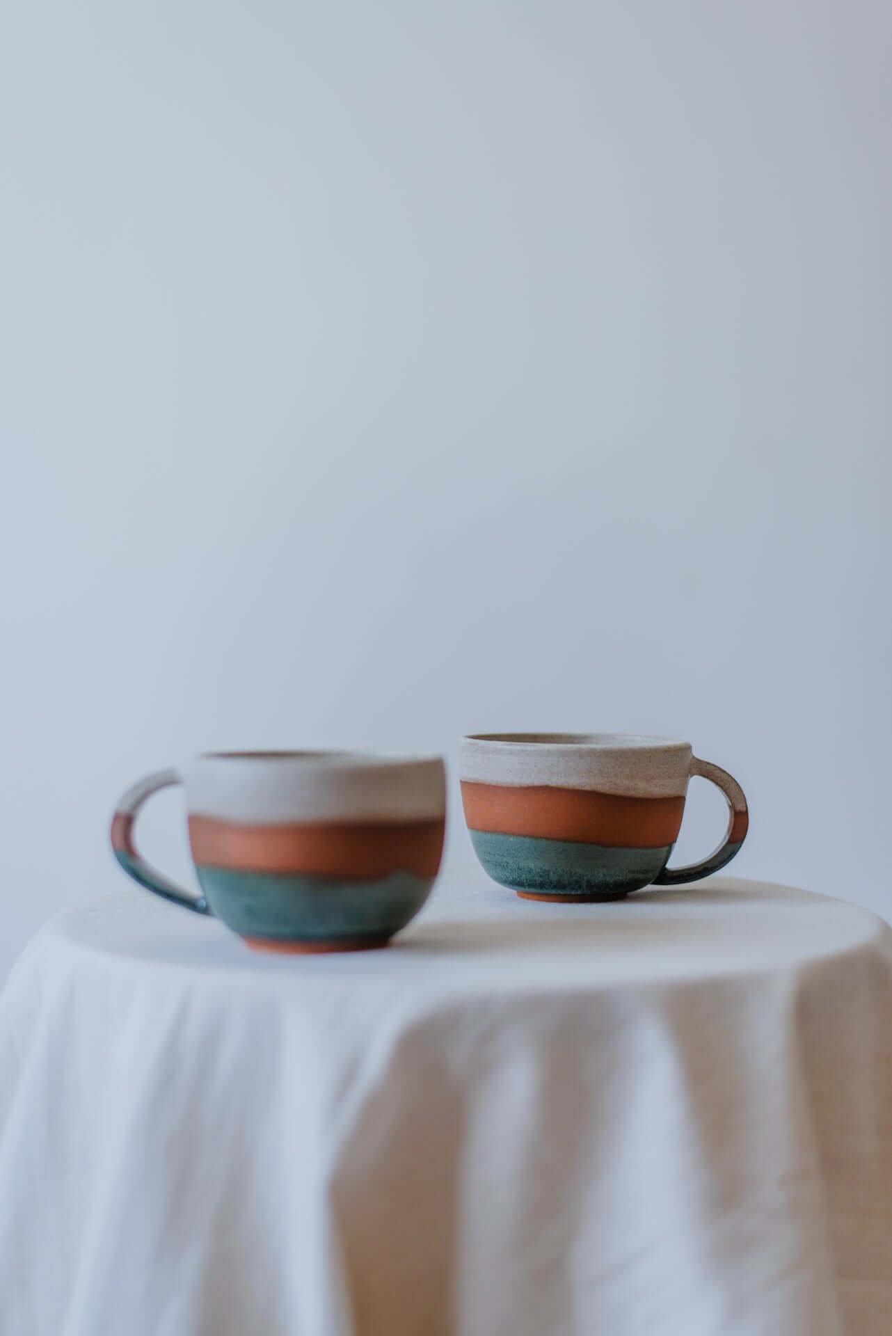 Handcrafted round ceramic cups with a smooth multicoloured glazed finish, ideal for serving beverages.