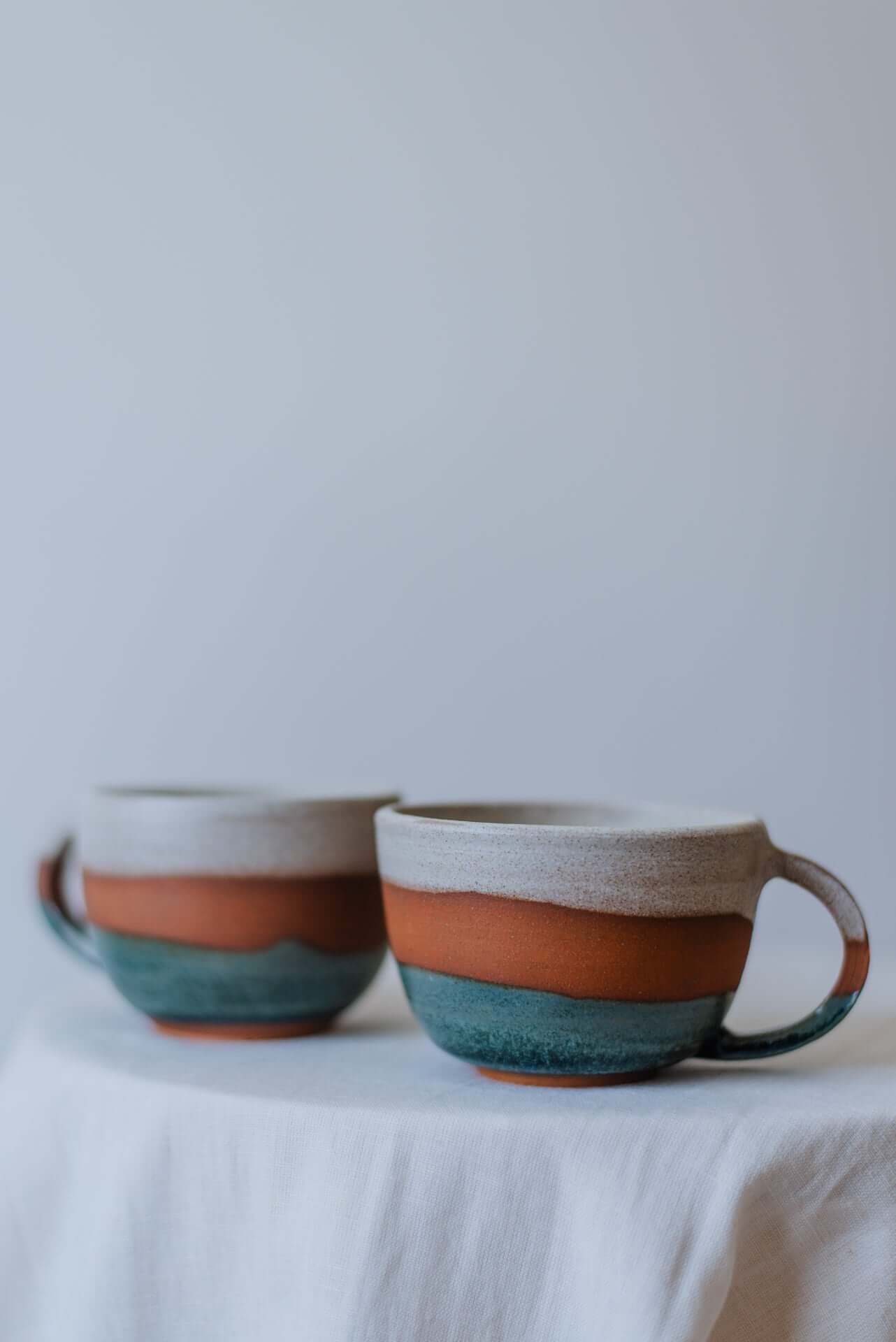 handcrafted round ceramic cups with a smooth, glossy finish, ideal for serving beverages.