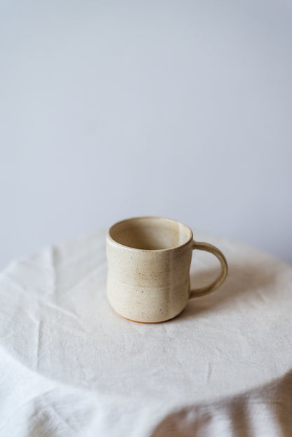 Handcrafted rustic white ceramic cup with a smooth finish, perfect for enjoying hot beverages like coffee or tea. Håndlaget rustikk hvit keramikkkopp med en glatt finish, perfekt for å nyte varme drikker som kaffe eller te.