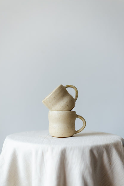 Handcrafted rustic white ceramic cup with a glossy finish, perfect for serving coffee, tea, or other hot beverages. Håndlaget rustikk hvit keramikkkopp med en glatt finish, perfekt for å nyte varme drikker som kaffe eller te.