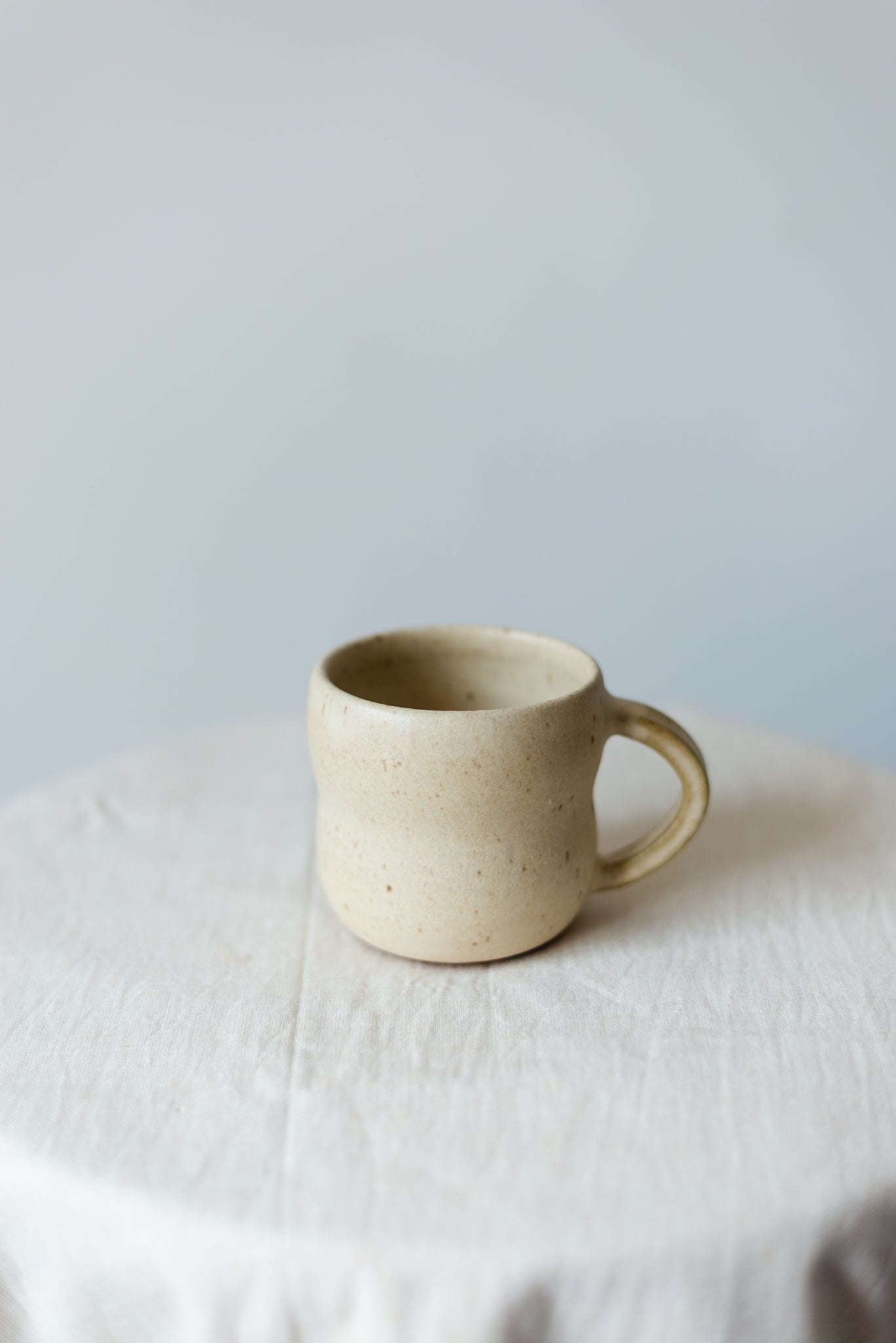 Handcrafted rustic white ceramic cup with a smooth finish, ideal for serving tea, coffee, or other hot beverages