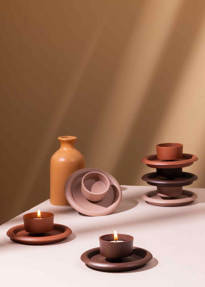 Set of ceramic items including vases, bowls, and candle holders on a white surface with a warm brown background.